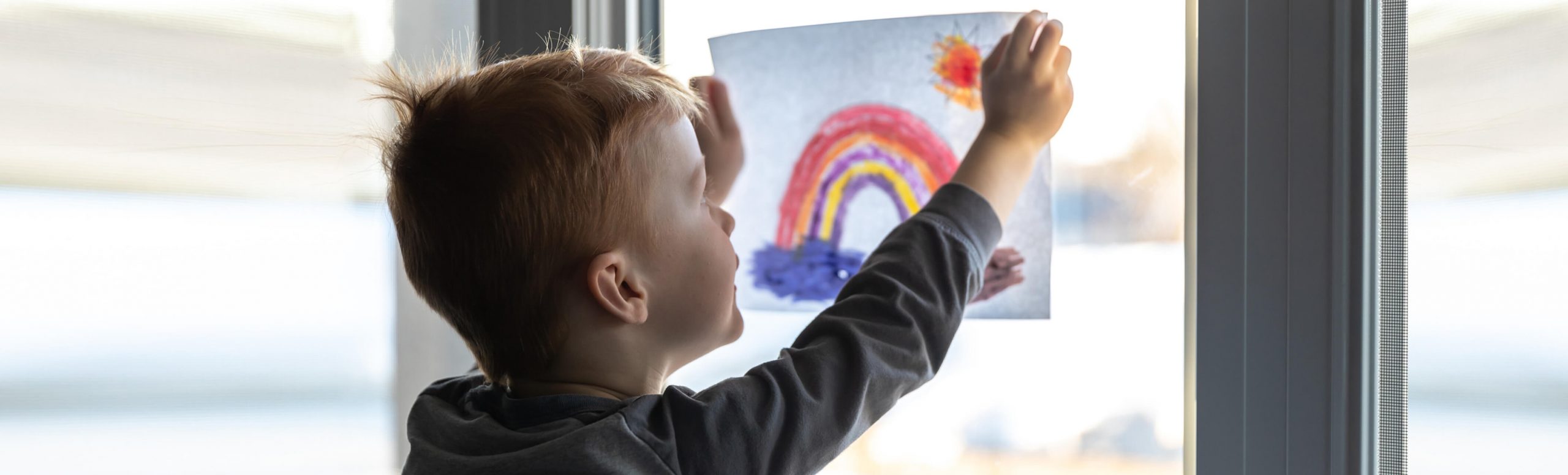 一个小男孩把他的画举到窗前。