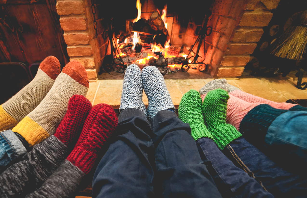 腿的观点，幸福的家庭穿着温暖的袜子在壁炉前-冬天，爱和舒适的概念-集中在中心灰色羊毛袜子